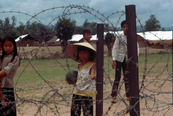 At the fence
Vietnamese children observe through a concertina wire fence.
