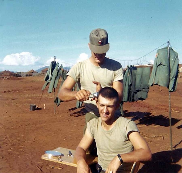 "Base Camp" Haircut
Getting a haircut while part of my wash (see the green fatigues?) is hanging in the background.  Note the 2/9th insignia on the barber's cap.
