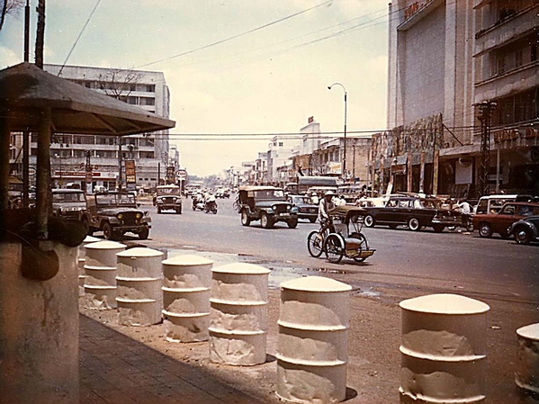 The Metropole
Looking out front the guard post in front of the Ky-Son billet to the intersection of Tran Hung Dau St and another street that angled off from it. The pedicabs were called "Cyclo" (sick-low) by the Vietnamese. The tall, smooth front building to the right was a Vietnamese theater  (I actually went in once and saw a show with my girlfriend- even though you weren't supposed to). The building off to the left is- OHHhhhhh yesssss... the French colonial hotel... The Metropole.
