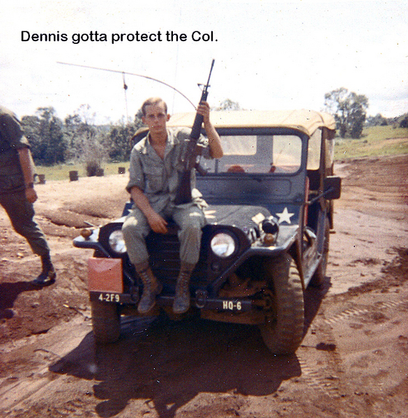 Protecting the Colonel
Dennis Couch holds M-16 while guarding the Colonel's jeep. He was the Colonel's driver for 2 months.  While in the Ammo Section, we all had to work every day supplying ammo, being on the road, and pulling Guard Duty at night.  Dennis grabbed the chance to be the Colonel's driver but returned to the Section with the move back to Camp Enari.
