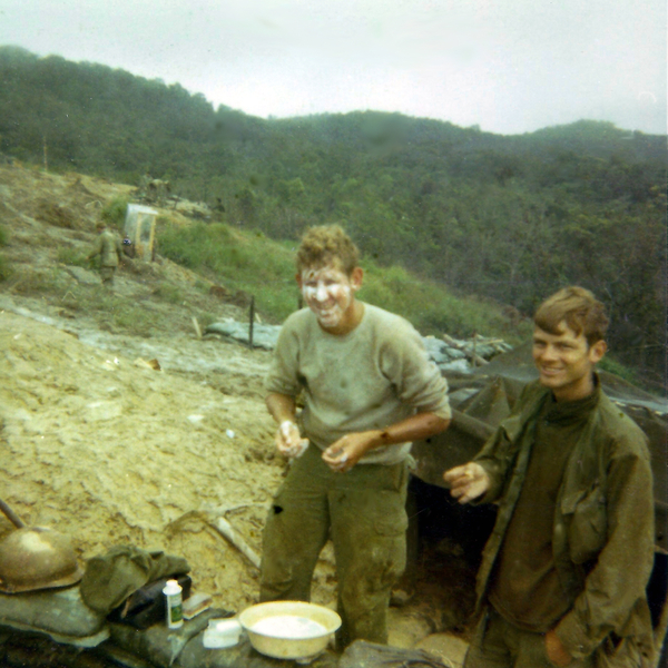 LZ Tuffy - 1970
Clean up time.  (L to R: Eugene "George" Jarisch and Mike Medley).  When those of us in the advance party (that didn't find the punji stakes) out of the 4 slicks that made it, we were stranded in the clouds without commo, in the mud inundated with 50 gallon drums of persistent CS.  Each morning, a dink from the group on the overlooking ridgeline would come up the draw and let off a clip trying to get us to fire back to locate our 60s.  It was only fitting that the three-holer (top left in photo) was placed in that shitty location.  I was hesitant to use it since it was on  the draw and left one's backside facing the dinks on the opposing ridgeline.
