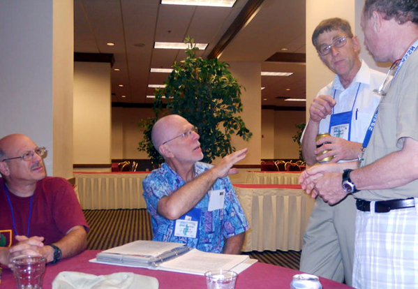 Hospitality Suite
John "Moon" Mullins makes a point about his scrapbook with fellow guests.

