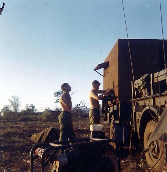 "Base Camp" - Jan 1966; FDC Trailer brought over from Hawaii
Center & Right: PFC Richard A. Williams & Sp4  Larry L. Black. They are shaving facing the FDC.  We had been in-country from two to four days at this point.  The  FDC for "B" Battery was a 3/4-ton truck with generator.   The FDC was known as the "Pink Kitty"; it was pink inside.  It was made of plywood and brought over from Hawaii.   See next photos for the progression of our FDC housing.
Our "wash area" is located where my right foot is.
